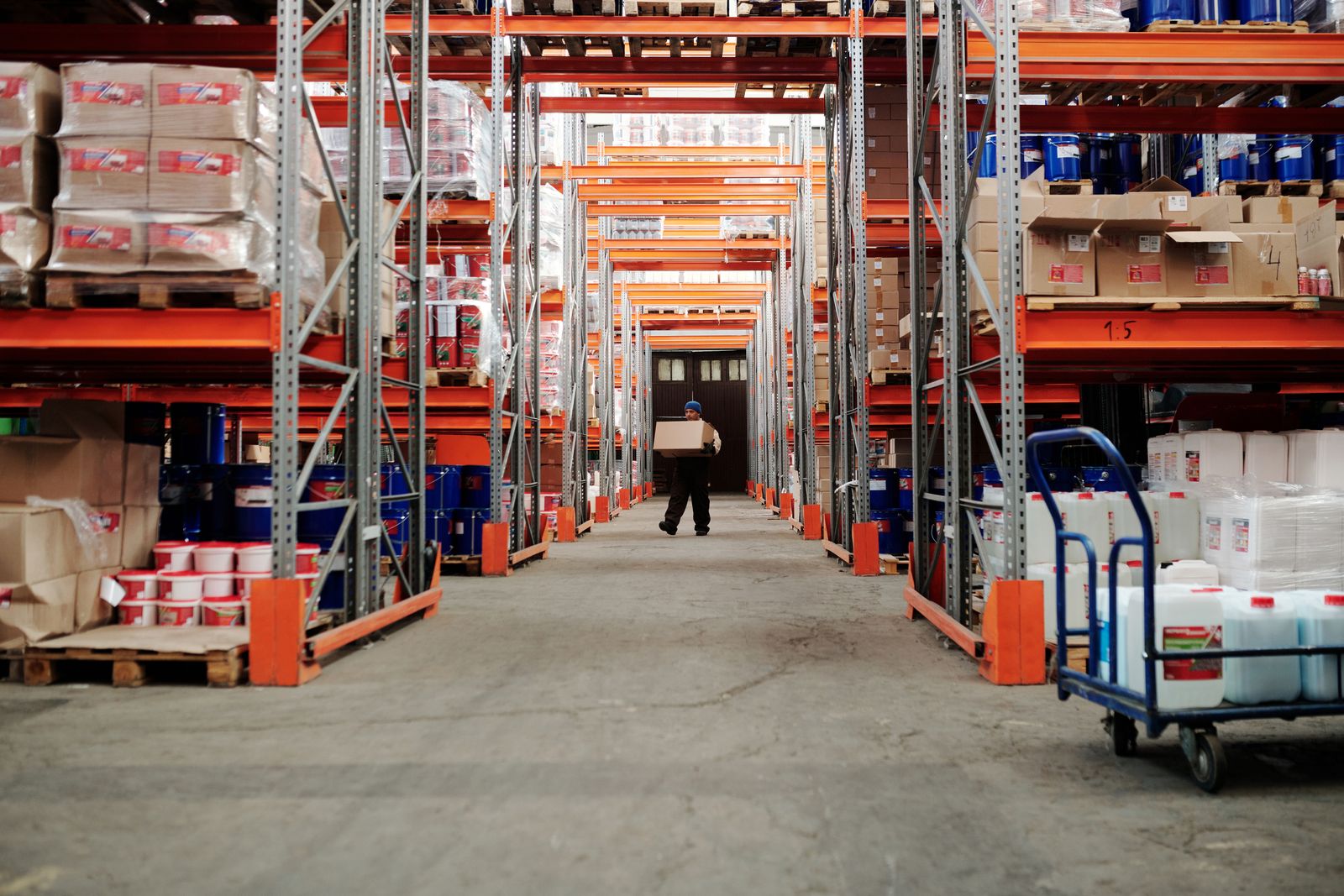 A warehouse employee carrying a carton down an aisle